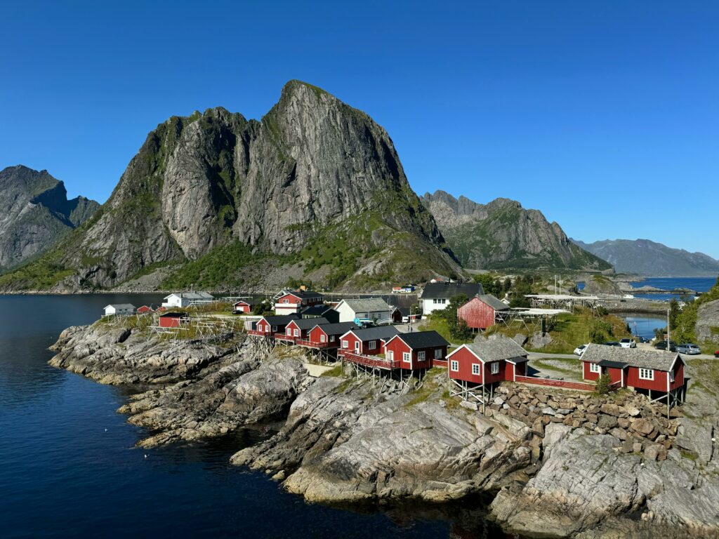 A picturesque Nordic village with red houses by the rocky coast and towering cliffs.