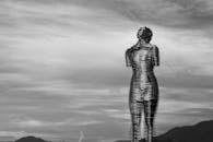 Black and white photo of a metal sculpture silhouette against a dramatic cloudy sky.