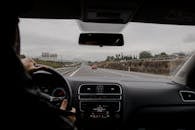 Anonymous man driving fast along asphalt road on modern vehicle in overcast weather